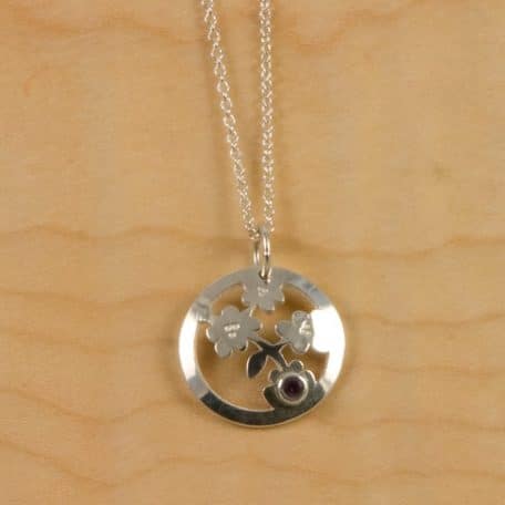 A silver Nara Blossom Pendant with an amethyst stone.