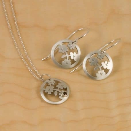 A set of sterling silver earrings and a pendant featuring the Nara Blossom design.