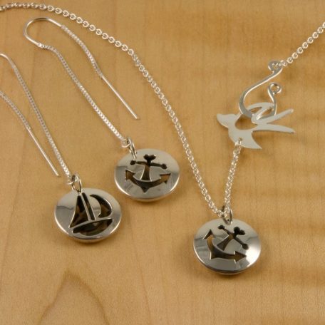 A pair of silver boat pendant necklaces and earrings.
