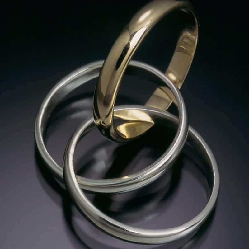 Three custom gold and silver rings stacked on top of each other.