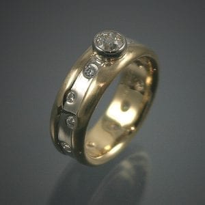 A custom wedding ring with two diamonds and a yellow gold band.