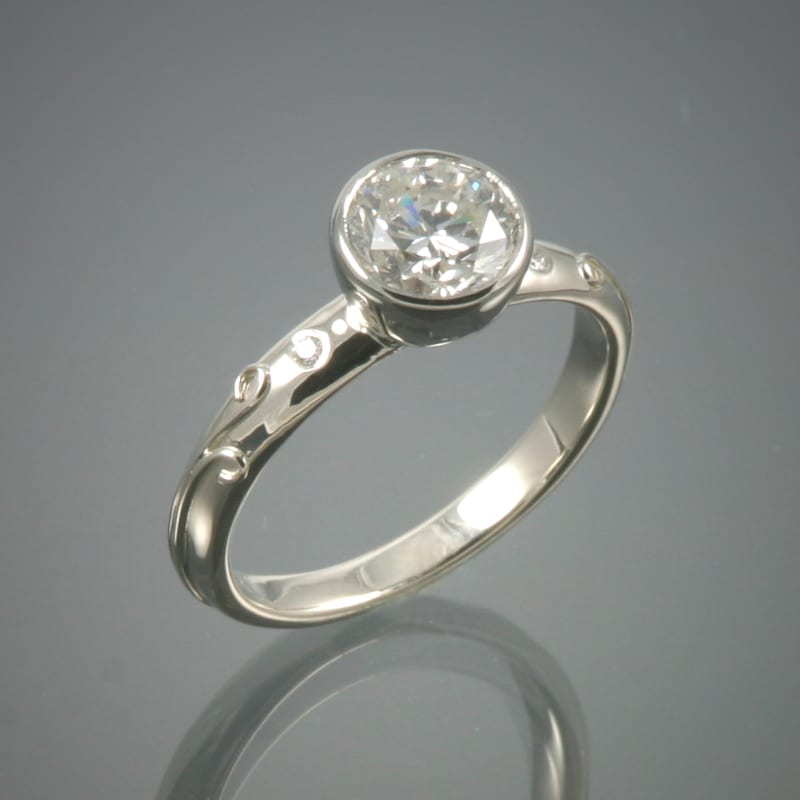 A custom white gold engagement ring with a round cut diamond.