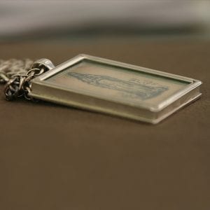 A custom silver necklace with a picture on it.