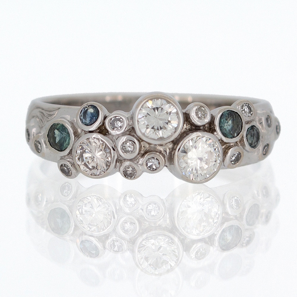 A custom white gold ring with diamonds and blue sapphires.