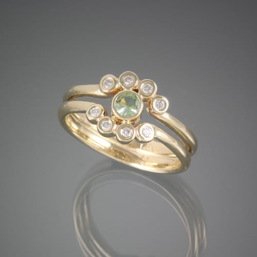 A custom yellow gold ring with a green tourmaline and diamonds.